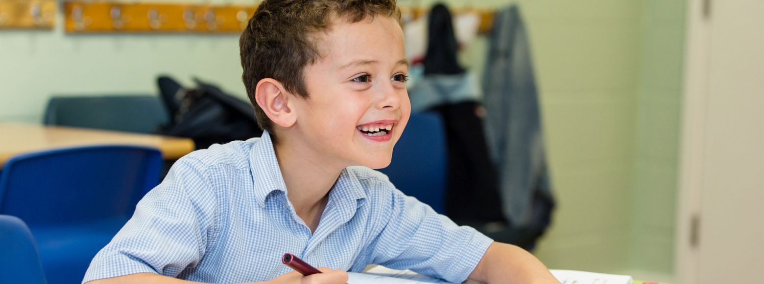 A child doing schoolwork and smiling at a London private school