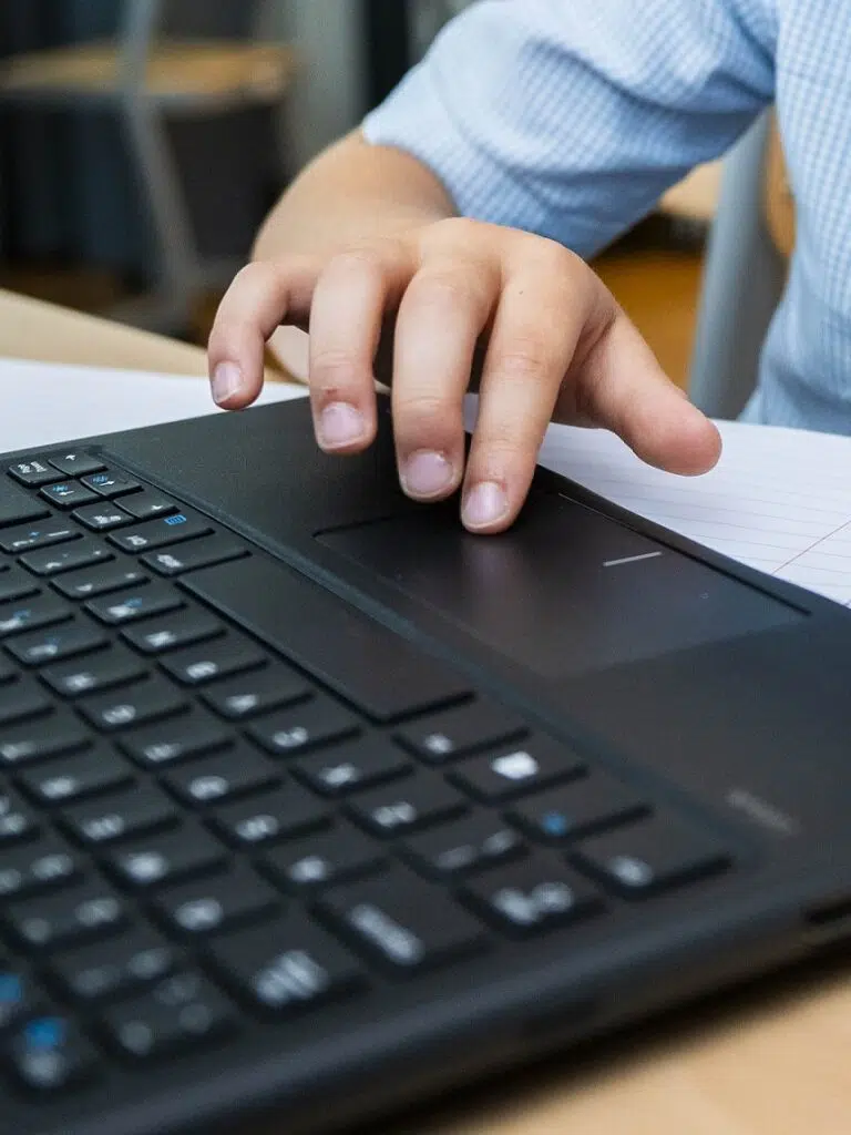 Close-up of a person's hand using the laptop touchpad beside a keyboard.