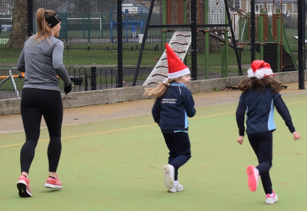 Children wearing santa hats running down the pitch