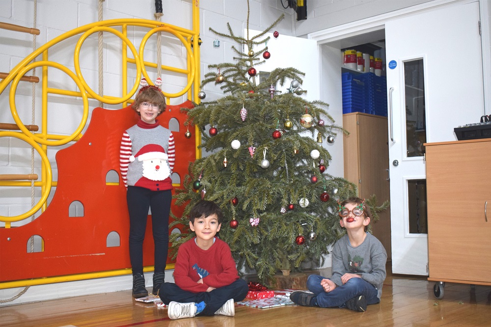 Children around a Christmas tree wearing Christmas jumpers at London prep school
