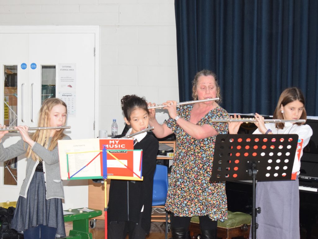 students and a teacher playing the flute