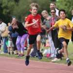 2 boys running on the athletics track