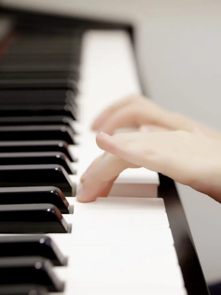 Close-up of fingers pressing white piano keys, hands in motion over the keyboard.