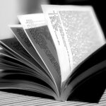 Open book with pages fanned out on a striped surface (black-and-white photo).