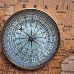 Compass with a blue face showing cardinal directions resting on a vintage map.