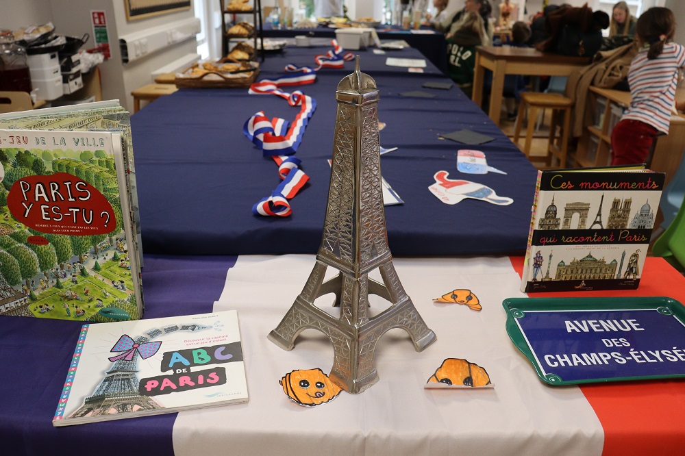 Miniature Eiffel Tower centerpiece on a Paris-themed display table with books and a blue-white-red cloth color scheme.