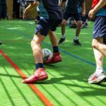 Youth soccer players dribble and contest a ball on a bright green turf surface outdoors.